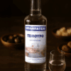 Auf einem Tisch steht ein Tsipouroflasche und auf der rechten Seite eine gefülltes Glas. Im Hintergrund sieht man Oliven und ein Brot